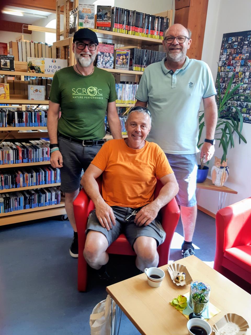 Drei Männer vor Buchregal